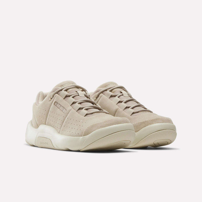 A pair of Reebok DMX Comfort+ Classic walking shoes in beige suede, designed with perforated sides, thick cream-colored soles featuring dynamic air cushioning, and matching beige laces. The shoes are displayed side by side on a plain white background, angled slightly to the right.