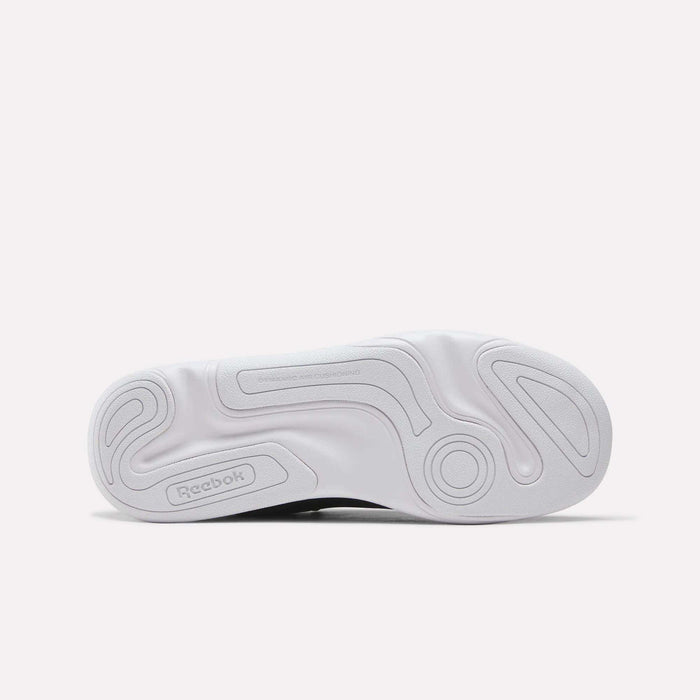 The image displays the white, textured outsole of the Reebok DMX Comfort+ Classic walking shoe, featuring circular and wavy grip patterns along with the Reebok logo near the heel—details that complement its premium leather upper.