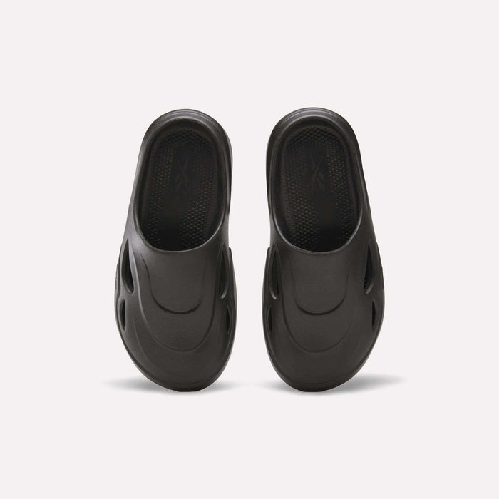 The Reebok DMX Recovery Mules are black, molded EVA slip-ons with DMX Moving Air tech, a textured footbed, and oval side vents, displayed from above on a white background.