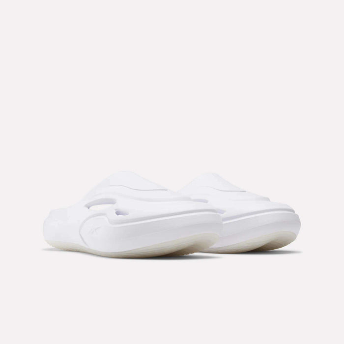 A pair of Reebok DMX Recovery Mules in white with a minimalist, slip-on design and thick molded EVA soles, displayed on a plain light background.