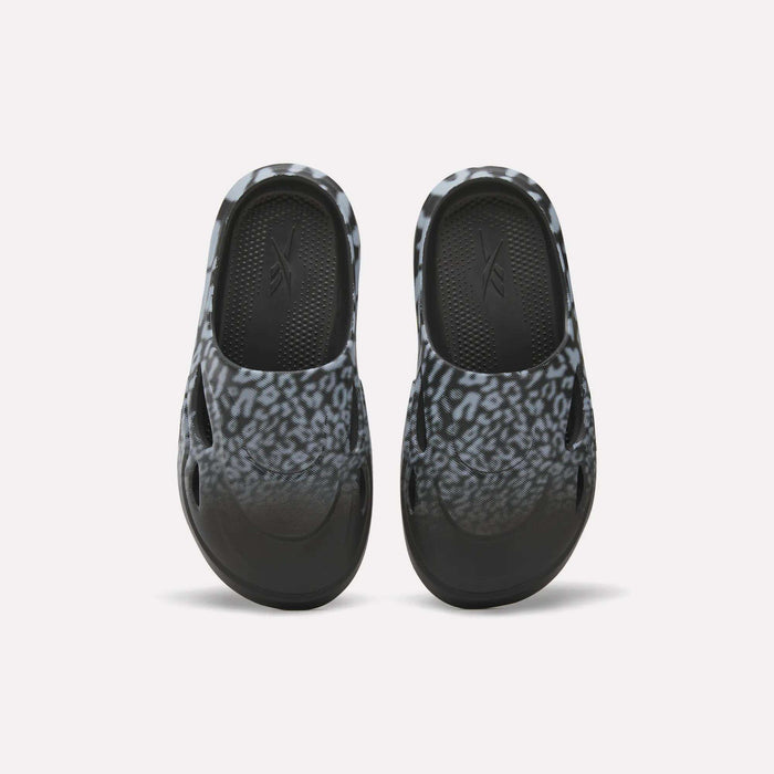 The Reebok DMX Recovery Mules feature a black and gray leopard print, shown from above on a white background—ideal recovery footwear after long days.