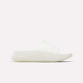A side view of the Reebok DMX Recovery Walking Slides, a minimalist all-white sandal with super-soft foam and a ridged, textured sole and upper, displayed against a plain white background.