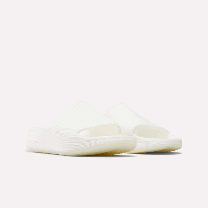 The Reebok DMX Recovery Walking Slides are white, open-toe recovery slides with a textured ribbed design and air cushioning, shown on a plain white background.