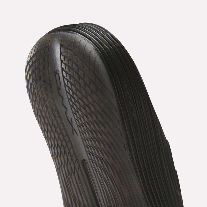 Close-up of the black, textured sole on Reebok DMX Recovery Walking Slides, showing DMX moving air cushioning along the side and detailed ridged patterns for enhanced grip.