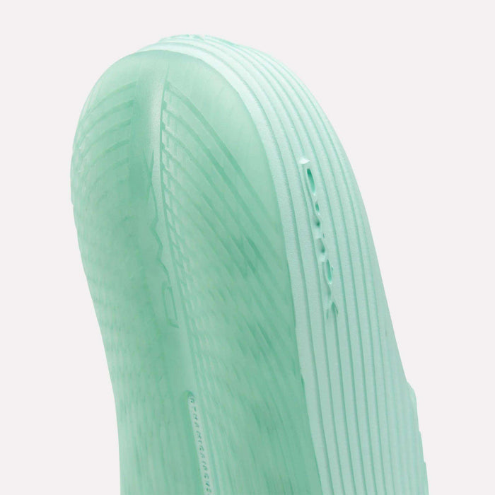Close-up of the mint green sole of Reebok’s DMX Recovery Walking Slides, featuring textured ridges and embossed DMX text—a reference to the brand’s moving air cushioning technology.