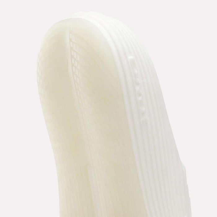 Close-up of the white, textured sole of Reebok DMX Recovery Walking Slides, showing visible grooves, ridges, and air cushioning against a plain light background.