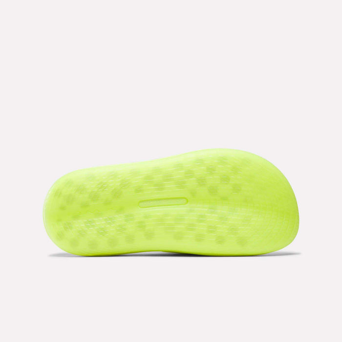The image shows the bright yellow sole of the Reebok DMX Recovery Walking Slides, viewed from below. The sole has a patterned, textured grip, moving air cushioning, and a small horizontal slot in the center.