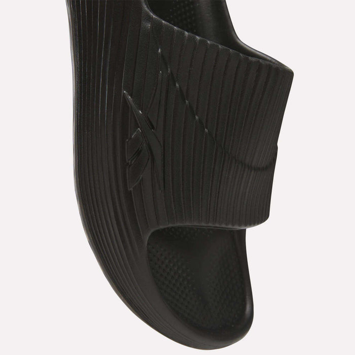Close-up of a black Reebok DMX Recovery Walking Slide featuring a textured strap with the embossed Reebok logo, ridged sole, and super-soft foam for all-day comfort.