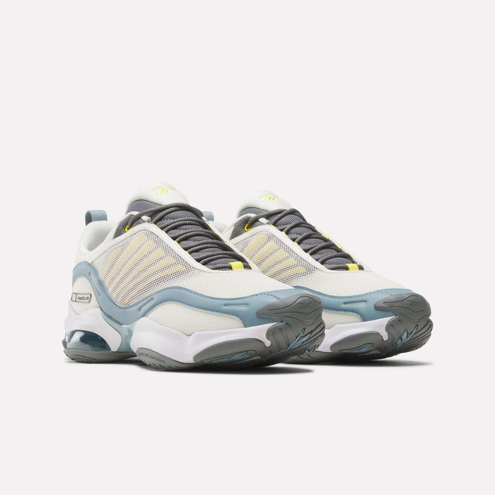 The Reebok DMX Series 3000 Shoes feature a white and light yellow mesh upper, blue and gray accents, yellow details, chunky textured gray soles, and DMX moving air technology in the heels for added comfort.