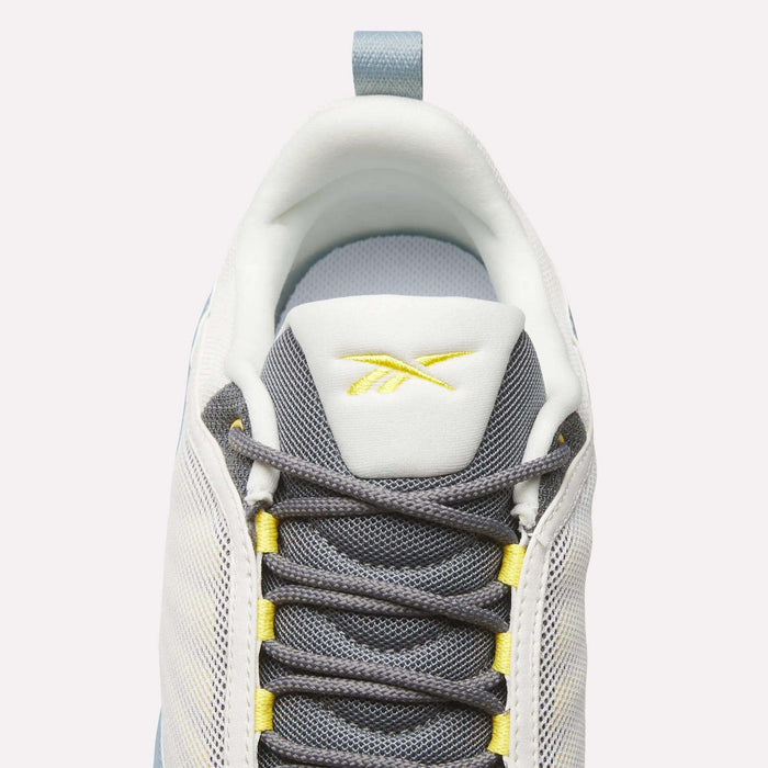 Top view of Reebok DMX Series 3000 Shoes in white and grey with yellow accents, dark grey laces, DMX moving air technology for comfort, and a yellow Reebok logo on the tongue, set against a light background.