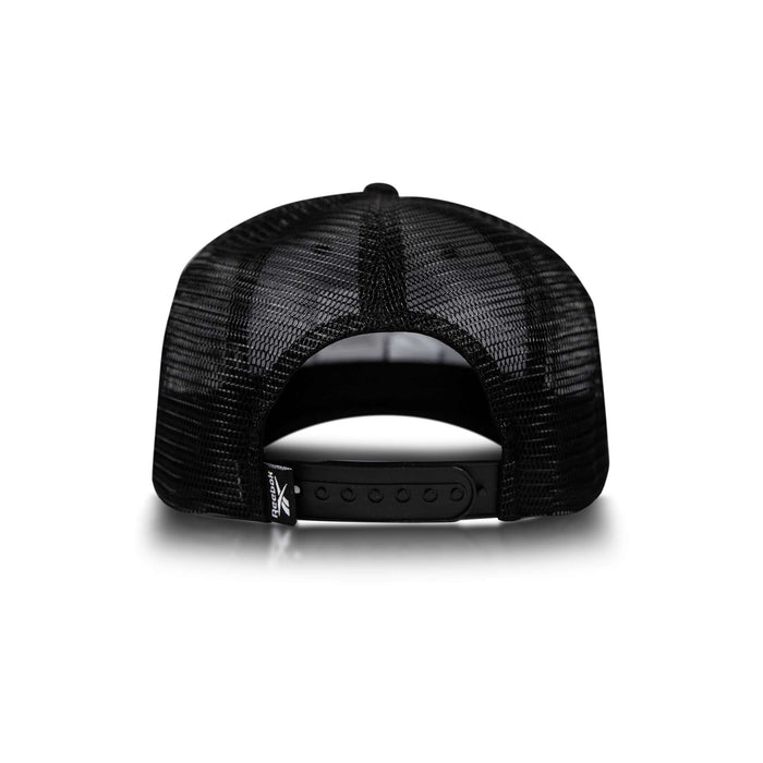 The Reebok Embroidered Vector Trucker Cap is shown from the back, featuring black mesh, an adjustable snapback strap, and a small fabric tag on the lower left of the opening against a white background.
