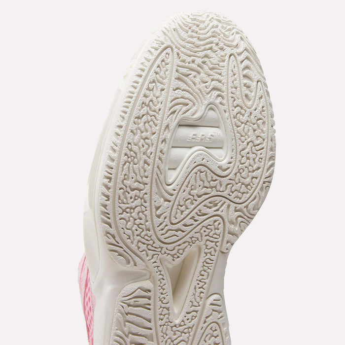 Close-up of the white textured sole on Reebok's Engine A 26 Basketball Shoes, featuring intricate patterns and JUMPMAN embossed at the center; part of the pink and white upper shows off the shoe’s style and stability.