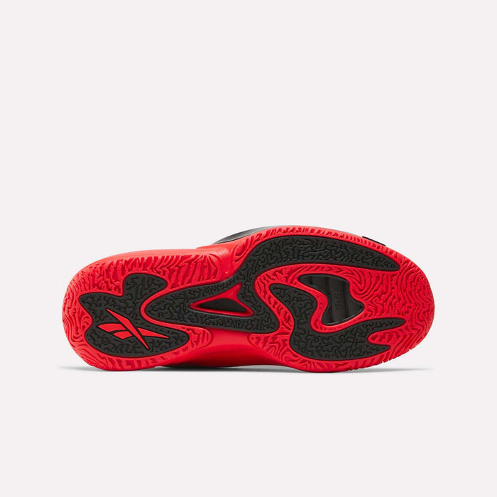 The image displays the sole of Reebok's Engine A 26 Basketball Shoes, mainly red with black wavy patterns and textured grip for stability. The Reebok logo appears in black on the left side of these sneakers.