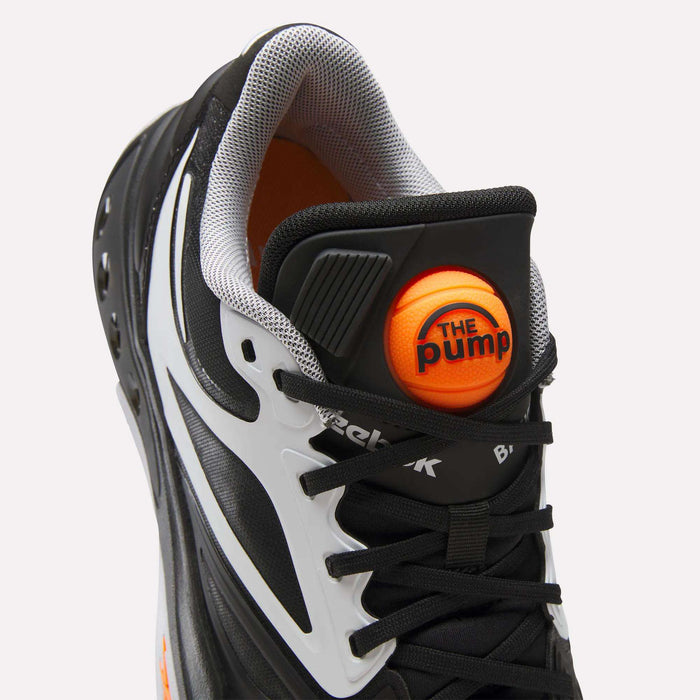 Close-up of a black and white Reebok Engine A Pump Shoes sneaker featuring an orange The Pump button on the tongue and black laces, showcasing classic Pump technology inspired by performance basketball shoes.