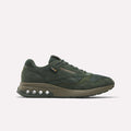 The ERS World Shoes by Reebok are dark green sneakers made with suede and CORDURA mesh. Featuring a chunky sole with circular pods and Energy Return System, these retro running shoes display the Reebok logo on the side against a white background.