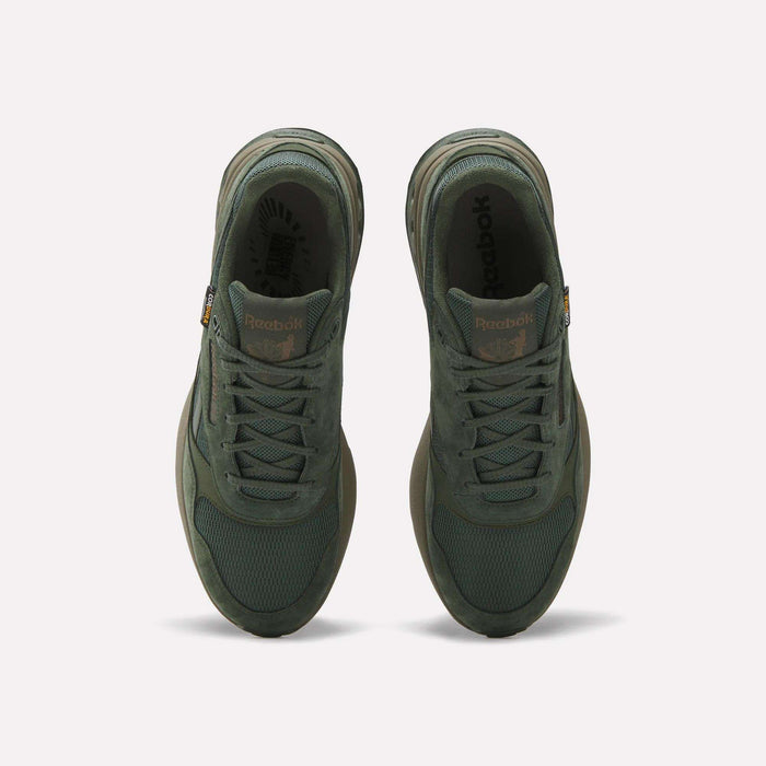 Top view of a pair of green Reebok ERS World Shoes with CORDURA mesh and suede details, side by side on a light background. The Reebok logo appears on the tongue and insole of each shoe.
