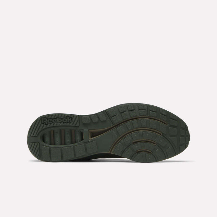 The image displays the bottom of a dark green Reebok ERS World Shoe, showcasing textured grip patterns and the embossed Reebok logo near the heel—retro details inspired by classic running shoe designs.