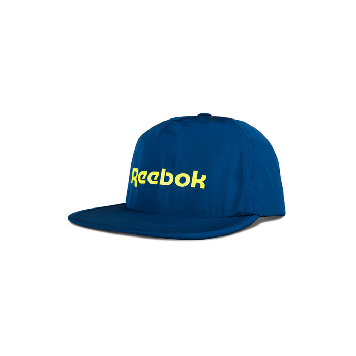 The Reebok Flat Brim Running Cap is a lightweight blue running hat with yellow Reebok branding on the front, moisture-wicking fabric, and is displayed on a white background.