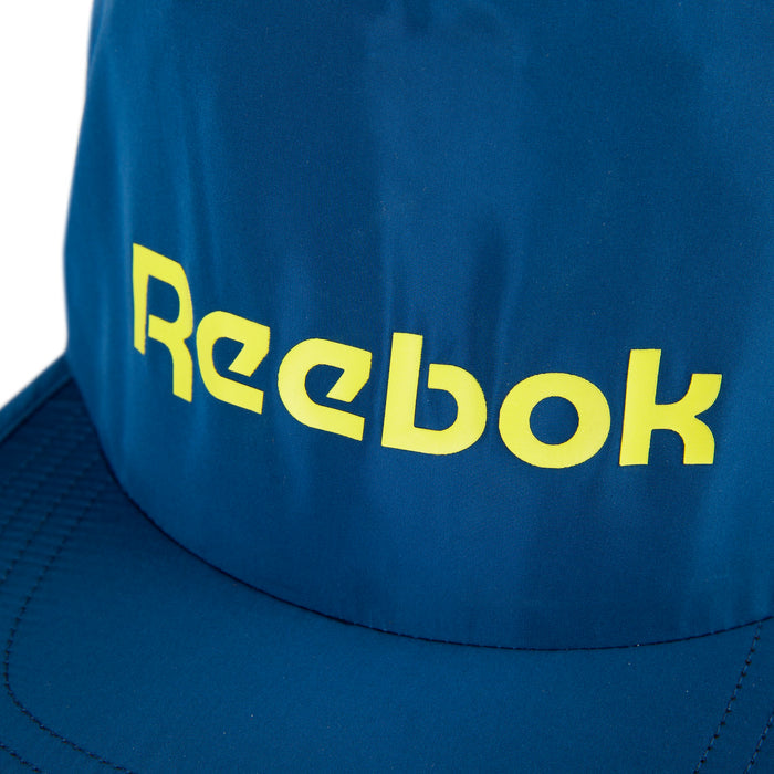 A close-up of the Reebok Flat Brim Running Cap in blue, featuring a yellow logo on the front. This lightweight cap uses moisture-wicking fabric to keep you cool and comfortable during workouts.