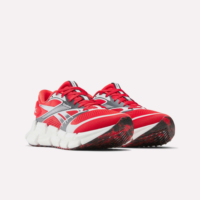 A pair of Reebok FloatZig 2 running shoes in red, gray, and white with chunky white soles featuring Superfloat+ cushioning, black-and-red patterned outsoles, and a supportive upper displayed on a plain white background.