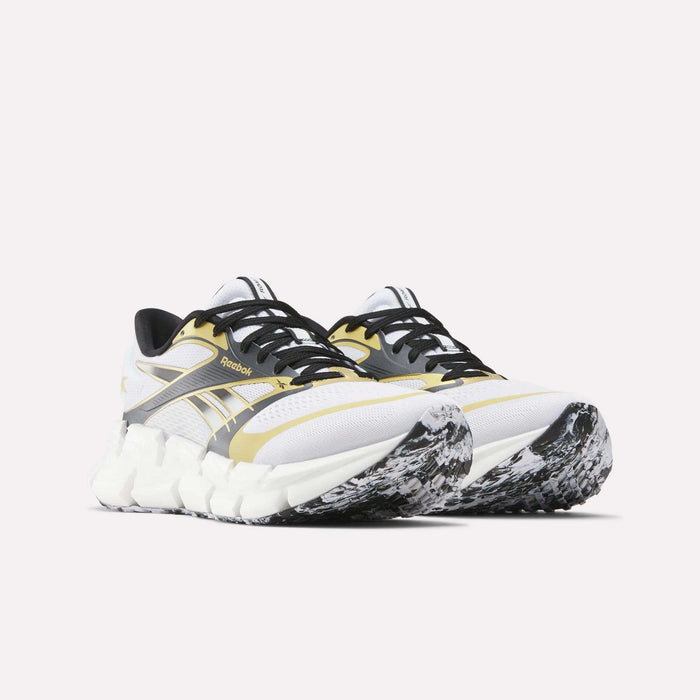 Reebok FloatZig 2 Running Shoes in white, black, and yellow feature chunky, textured soles with a black-and-white marbled pattern and Superfloat+ cushioning. Displayed on a plain light background.