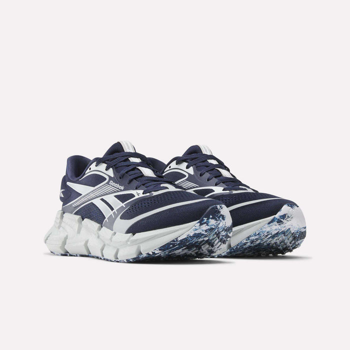 A pair of Reebok FloatZig 2 Running Shoes in navy blue and white, featuring Superfloat+ cushioning, a chunky white sole, and a blue, white, and gray patterned outsole displayed on a light background.