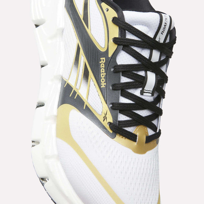 Close-up of a white Reebok FloatZig 2 Running Shoe with black laces, gold and black accents, and a chunky Superfloat+ cushioned sole. Energy-returning design and the iconic Reebok logo appear on the side.