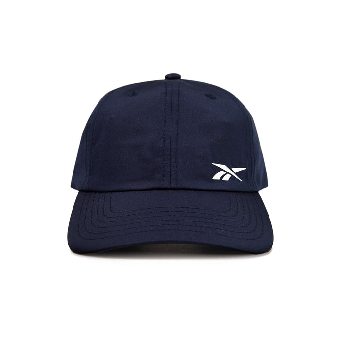 A front view of the Reebok Flow Cap in navy blue, featuring a small white Reebok logo on the left crown and a moisture-wicking sweatband for comfort.