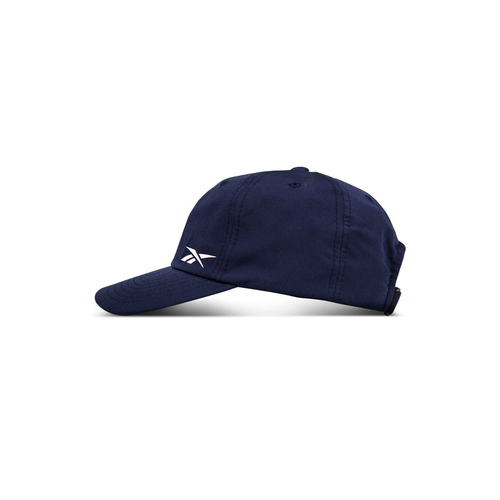 The Reebok Flow Cap is navy blue with a curved brim and white embroidered logo. Made from recycled polyester, it features a moisture-wicking sweatband and is shown against a plain white background.