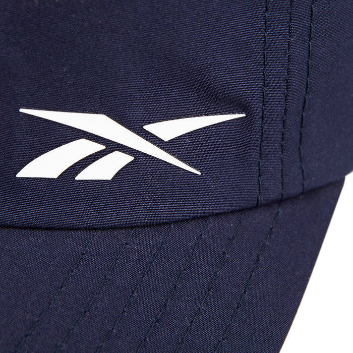 Close-up of the Reebok Flow Cap in navy blue, made from recycled polyester. Features a white Reebok logo near the stitched seam and a moisture-wicking sweatband for comfort.