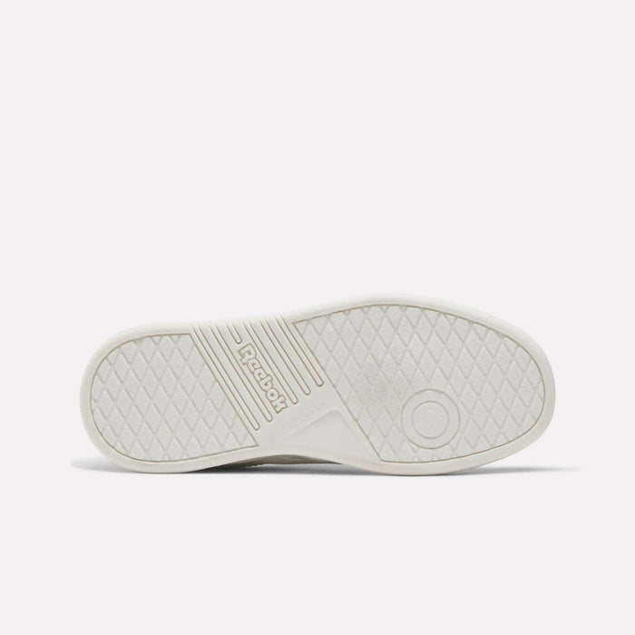 The image displays the white sole of the Reebok Forte Pitch Shoes - Little Kids, showcasing a diamond-patterned tread, a circular detail on the right side, and central Reebok branding—a subtle homage to its tennis-inspired design.