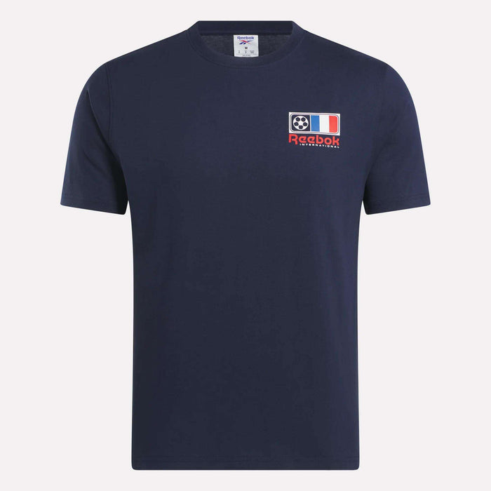 The Reebok France Football T-Shirt is a navy blue short-sleeve tee with a left chest patch featuring a football, the French flag, and "Reebok International" text—ideal for soccer fans.