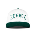 The Reebok Gameday Cap features a white crown, a dark green curved brim, and large green REEBOK embroidery on the front.