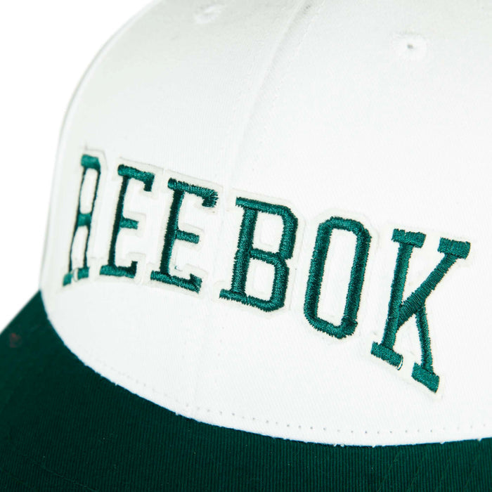 Close-up of the Reebok Gameday Cap, featuring a white and green design with "REEBOK" embroidered in bold green letters on the front.