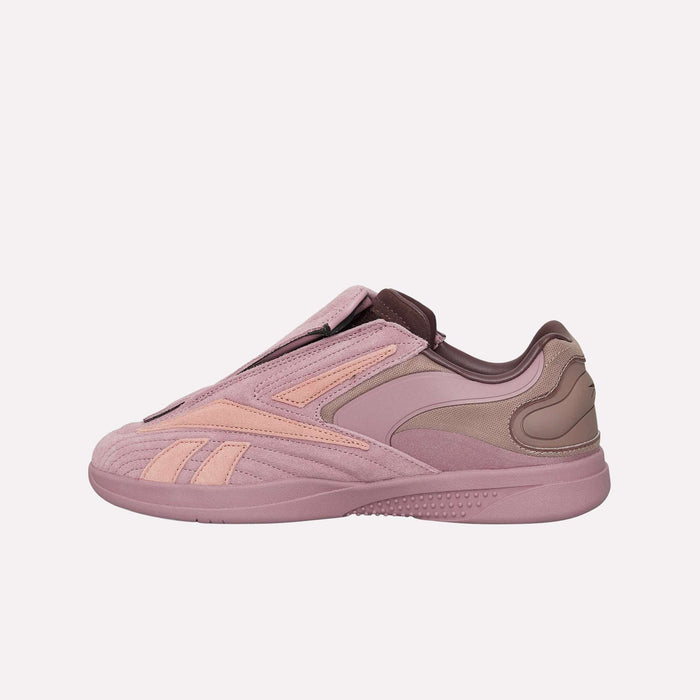 A side-view image of the Reebok Hammer Pro LTD Shoes showcases their pink and mauve colorway, featuring a premium suede upper with a sleek, layered design and a laceless silhouette, set against a plain light background.