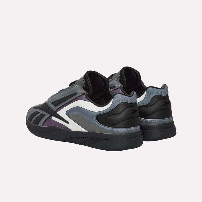 Two dark-colored Reebok Hammer Pro LTD Shoes with black, durable rubber soles; white accents; and purple and gray details feature a sleek faux leather upper. Shown from an angled rear view against a plain light background.