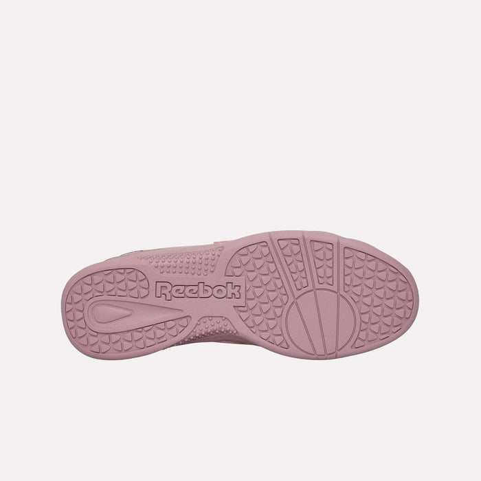 The image features the pink sole of the Reebok Hammer Pro LTD Shoes seen from below, highlighting the textured tread pattern and the Reebok logo embossed at the center. The durable rubber outsole provides lasting wear, perfectly complementing the stylish suede upper.