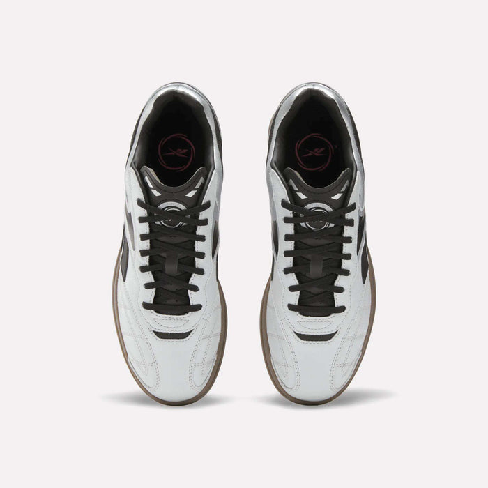 Top view of Reebok Hammer Street Shoes—soccer-inspired full-grain leather shoes with black laces, brown soles, and a pink logo on the black insole—placed side by side on a light background.