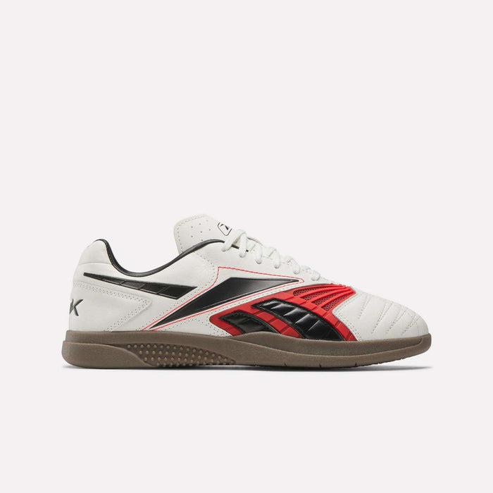 The Reebok Hammer Valde Shoes are white indoor soccer boots with red and black accents, a lace-up leather upper, low profile gum rubber sole, visible stitching, and classic Reebok branding on the side and heel.