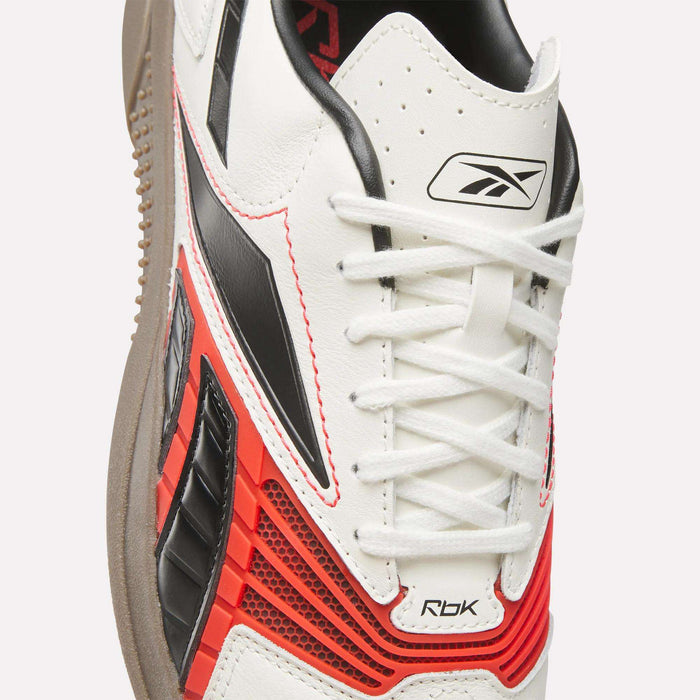 Close-up of the Reebok Hammer Valde Shoes in white, featuring black and red accents, a leather upper, brown sole, black Reebok logo on the tongue, red mesh details, and black side design elements.
