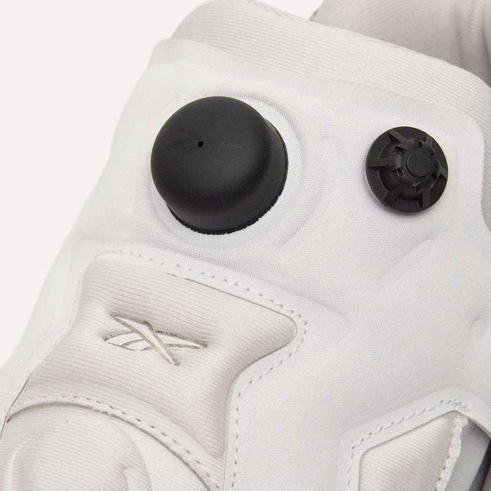 Close-up of a white Reebok Instapump Sliver LTD Shoe showcasing a visible air pump button and valve on the tongue, highlighted with embroidered Reebok branding and advanced Hexalite cushioning for superior comfort.