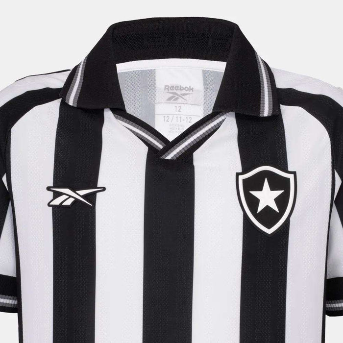 The Kids' Botafogo Youth Home Jersey by Reebok features classic black and white stripes, a collar, the Reebok logo on one side, and a shield with a white star—perfect for young fans of the 25/26 home shirt design.