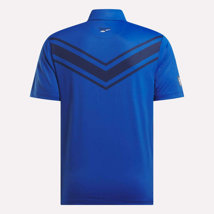 A back view of the Reebok Men's BDC Colorblocked Polo Shirt in blue, featuring RBK-DRY tech, two dark blue chevron stripes on the upper back and shoulders, and a small Reebok logo beneath the collar.