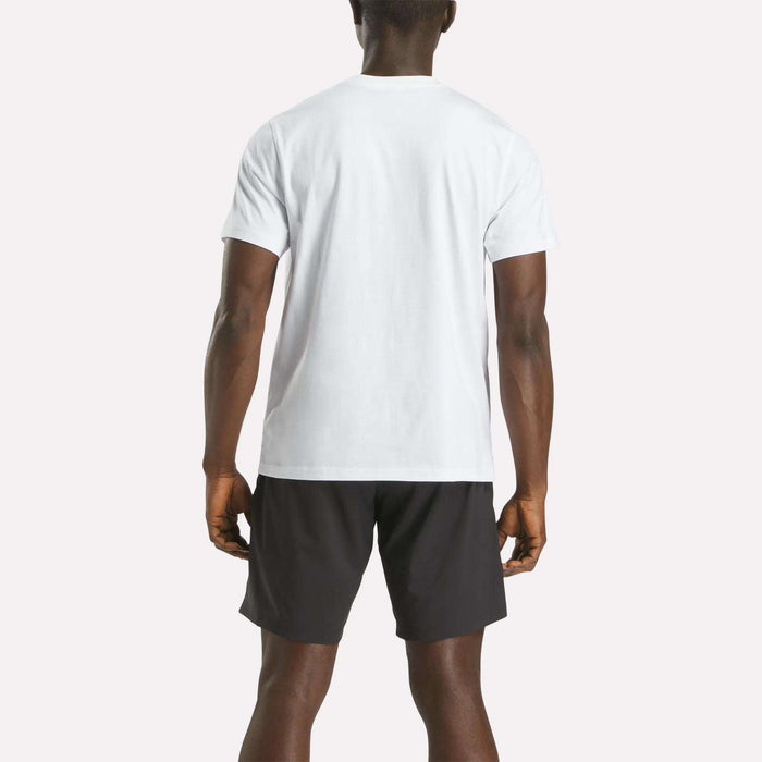 A man is facing away from the camera, wearing a Reebok Men's Big Logo Crewneck Short Sleeve Tee in white and black shorts, set against a light background.