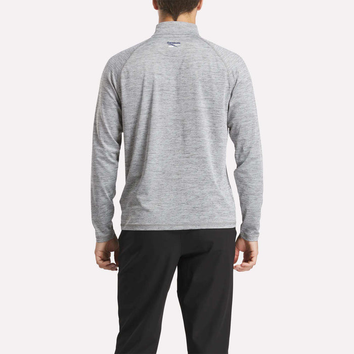 A person is seen from behind wearing a light gray Reebok Men's Cationic Wicking Quarter-Zip Sweatshirt and black pants, standing against a plain white background.