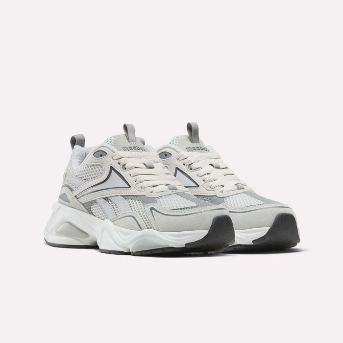A pair of Reebok Men’s Charge Shoes in light gray and white, featuring mesh and suede details, thick white soles with a cushioned midsole, and lace-up fronts, displayed on a plain white background.