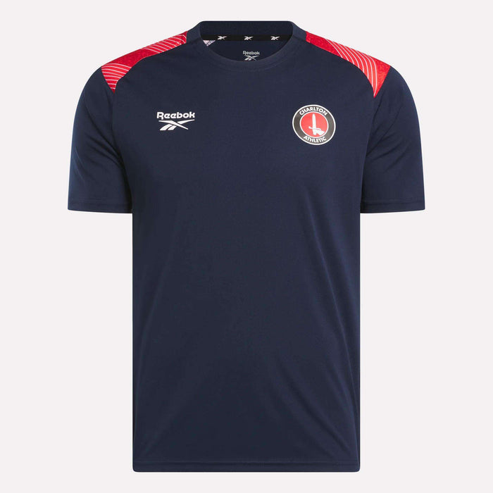 The Men's Charlton Training T-Shirt by Reebok features navy blue fabric, red shoulder details, a white Reebok logo on the right chest, and the Charlton Athletic crest on the left—perfect for devoted Charlton fans.