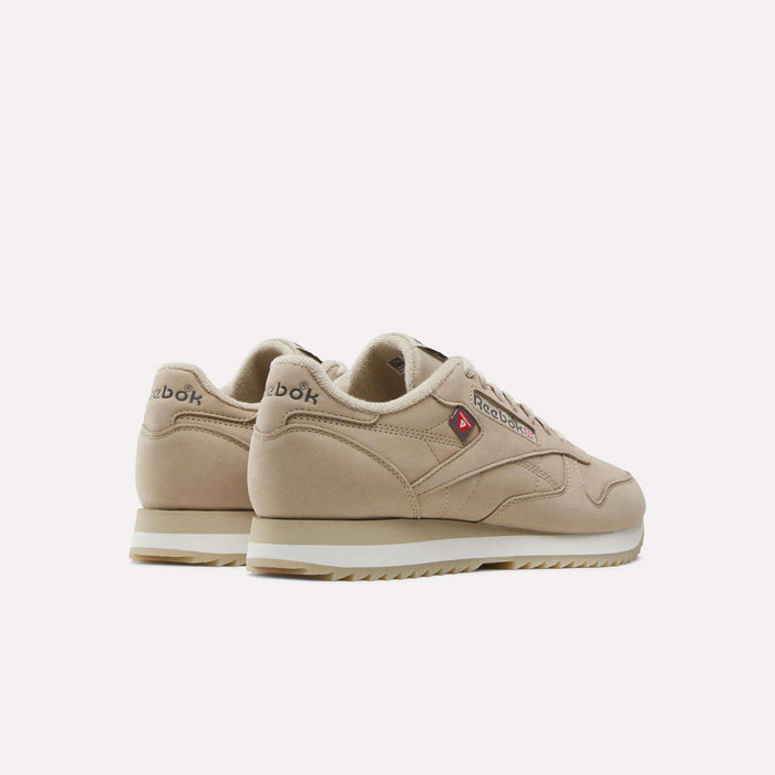 A pair of Men’s Classic Leather Ripple Shoes by Reebok in beige is displayed from the back and side, showcasing the signature Reebok logo along with a small red triangle detail on the side. The sneakers feature white soles with an EVA midsole for enhanced comfort and are set against a plain white background.