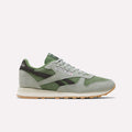 A pair of Reebok Men’s Classic Leather Shoes in Hazygreen, Legacygreen, and Gum is displayed from the side on a plain white background. These sneakers feature a timeless design inspired by the iconic Classic Leather silhouette and are equipped with an EVA midsole for enhanced comfort.