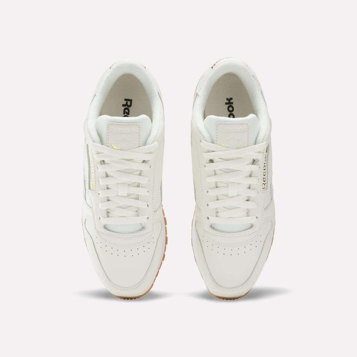 A pair of Men's Classic Leather Shoes by Reebok in white, shown from above with visible laces, perforated toe areas, and the Reebok logo on the sides and inside the shoes. Set against a plain white background, these sneakers also include an EVA midsole for lightweight cushioning.
